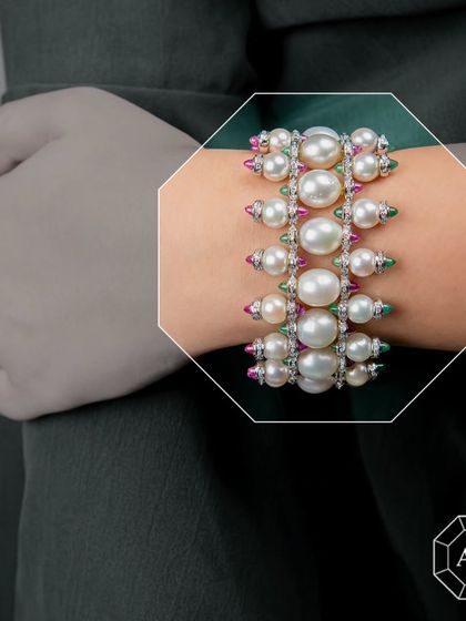 Our three-line South Sea pearl bracelet features radiant pearls, sparkling diamonds, and gold, finished with vivid rubies and emeralds.