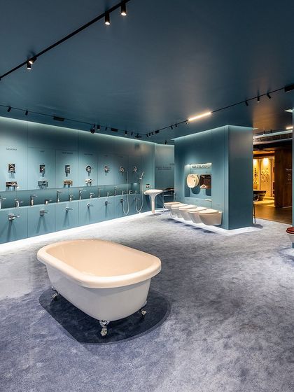 The lighting design is crucial, with spotlights aimed to prevent glare and highlight the form and texture of each bathroom fixture.