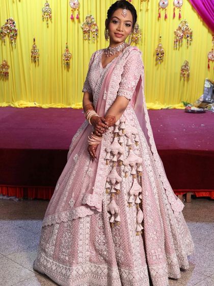 A client looking elegant in a pastel pink lehenga with unique tassel details. This outfit is a great example of modern bridal wear with a touch of tradition.