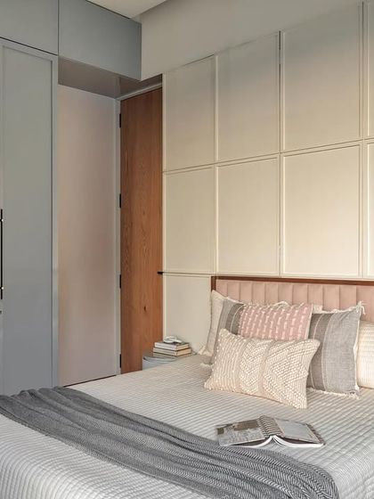 To add extra storage, I created a new wall with concealed storage behind MDF paneling. The grey PU finish wardrobes beautifully complement the blush-toned headboard, creating a harmonious and calming ambiance.
