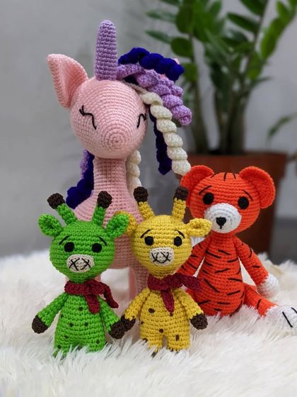 A set of handmade animal toys, including a pink unicorn, two colorful giraffes, and a tiger.