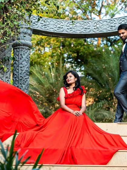 A creative composition on a set of stone stairs, with the bride seated in her flowing red gown, creating an elegant and artistic pre-wedding portrait.