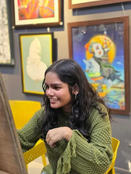 A student smiles while working on her charcoal drawing. We believe the process of creating art should be as enjoyable as the final result.