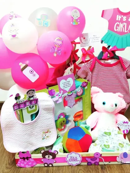 This 'It's a Girl' hamper is ready for a party. It comes with a cute pink outfit, a soft plush toy, a bib, and other essentials to celebrate the new arrival.