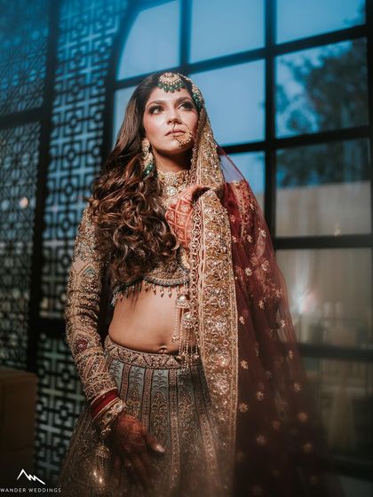 A moody and artistic shot of the bride. The makeup, with its defined eyes and contoured features, looks striking against the dramatic lighting.