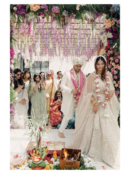 The couple performs the 'pheras' or circles around the sacred fire, a central ritual in a Hindu wedding. The vibrant floral decor and the focused expressions of the couple make this a powerful ceremony shot.