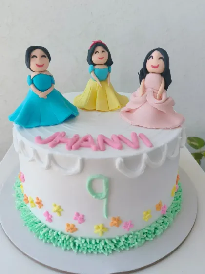 A custom cake featuring three personalized princess figures, handcrafted from fondant to resemble the birthday girl and her friends.