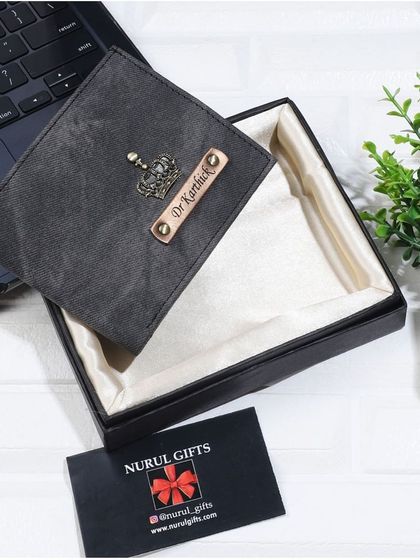 This personalized denim wallet in a dark grey color is customized with a crown charm and a 'Dr.' title, presented in its gift box.