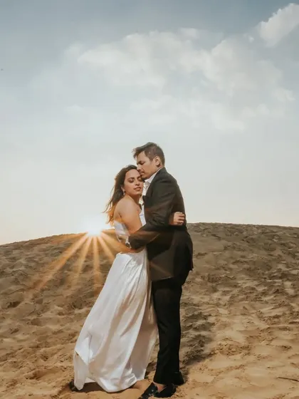 A romantic embrace on a sand dune at sunset. This destination shot uses the golden light and unique landscape to create a warm and dramatic pre-wedding portrait.