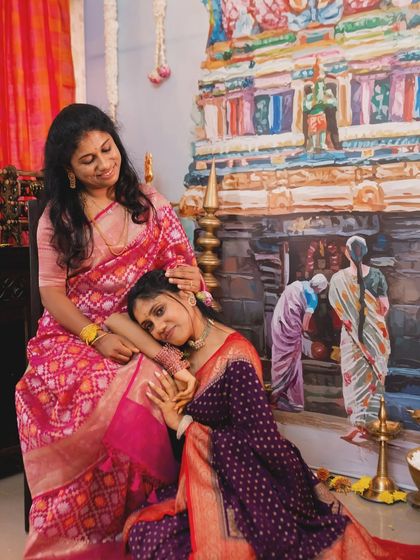 A heartfelt moment between a mother and daughter during the Chapra Pooje. The backdrop is a custom painting depicting a temple scene, adding a deeply personal and artistic touch to the ritual space.