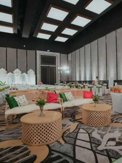 The guest seating area for a Myra ceremony, inspired by Good Earth, with natural wood furniture and colorful cushions.