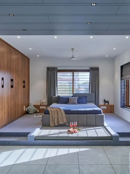 This unique bedroom features a split-level design, with the bed placed on a raised, carpeted platform. This creates a distinct sleeping zone and adds an interesting architectural element to the room.