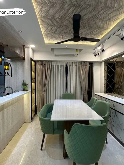 This view shows the dining area with a breakfast counter that has a fluted panel base. The industrial-style pendant lights add a unique touch to the space.