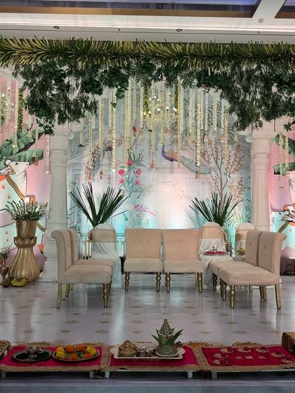 A full view of a grand Pichwai-inspired stage, featuring large painted cow motifs (Nandi), lush banana plants, and traditional pillars for a truly divine setup.