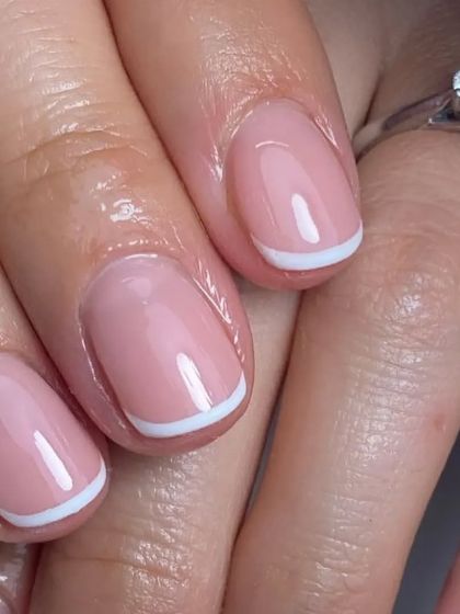 A close-up of a simple and clean French tip on a short, natural nail, showing our attention to detail.