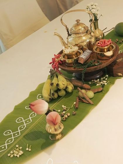 A long shot of a dining table decorated with a traditional banana leaf runner and brass elements.