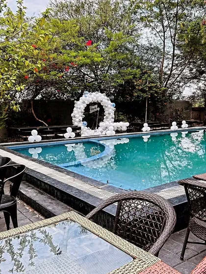 A simple and elegant poolside birthday decoration. A white balloon arch creates a beautiful focal point against the water, perfect for a daytime adult party.