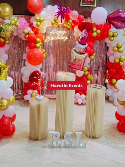 A fabulous makeup-themed party. This setup in red, pink, and gold features a balloon arch with lipstick and lip-shaped foil balloons, perfect for a makeup lover's birthday.