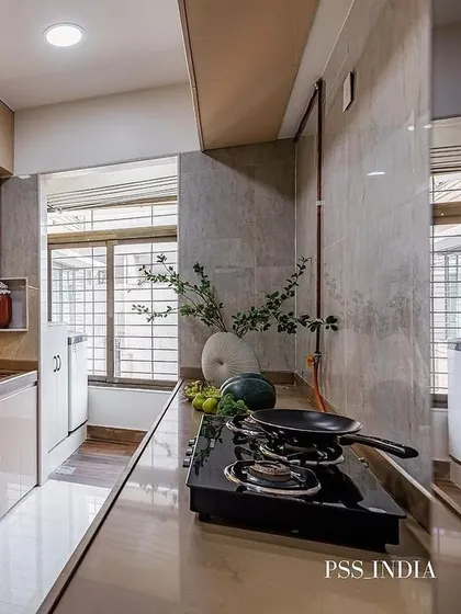 A beautifully styled kitchen counter with a large vase of greenery and fresh produce. The neutral stone backsplash and countertop provide a calm and natural backdrop.