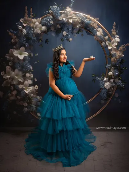A celestial queen. Framed by a ring of blue and white flowers, the mother-to-be holds a butterfly, symbolizing transformation and the magic of new life.