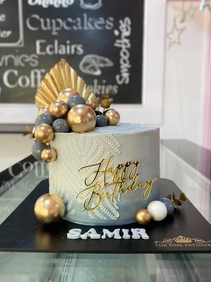 A stylish grey cake for Samir with a leaf-stencil design and a cascade of gold and grey spheres.