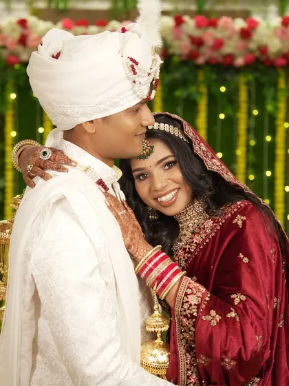 A sweet embrace, with the groom kissing his bride's forehead, capturing a moment of affection.