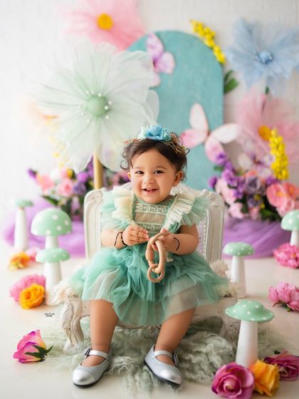 This little one's smile lights up the whole garden. A happy moment from her pastel-themed sitter session.
