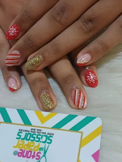 Getting into the festive spirit with this Christmas-themed nail art. The set includes hand-painted snowflakes, candy cane stripes, and a full-coverage gold glitter nail.