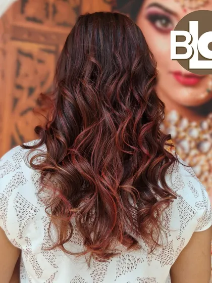 Another view of this beautiful red-toned hair, styled in loose waves. The bridal poster in the background reminds us that we get you ready for all occasions.