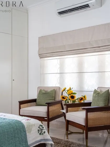 A pair of our classic lounge chairs with caned sides and solid wood frames, creating a cozy reading nook in a bedroom designed by Aurora Studio.