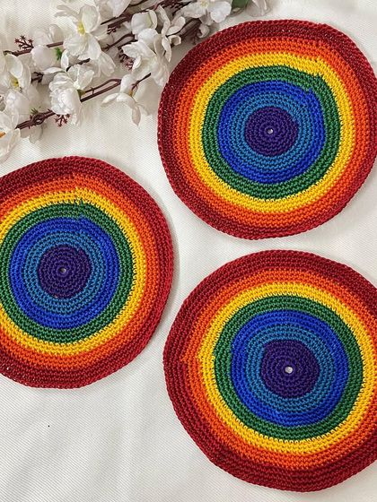 A set of three handmade rainbow doilies. These are perfect for adding a pop of color to a side table or for use as cheerful coasters.