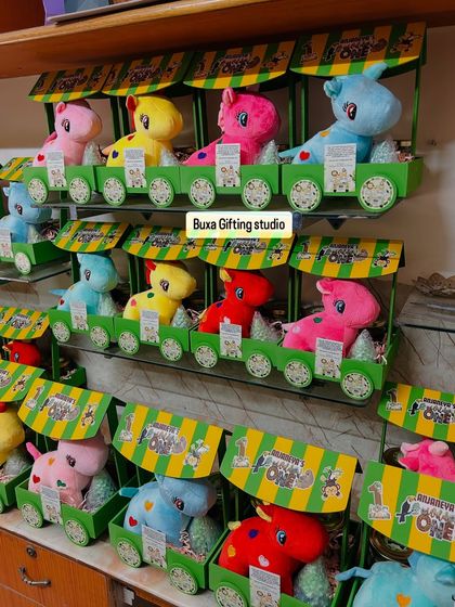 A full display of the "Jungle Jamboree" first birthday hampers, with colorful soft toys peeking out of the green carts.