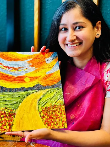 The proud smile of an artist holding her finished textured landscape painting. At our workshops, you'll learn palette knife techniques to create stunning 3D art like this, and you'll walk away with a piece you'll be proud to hang on your wall.