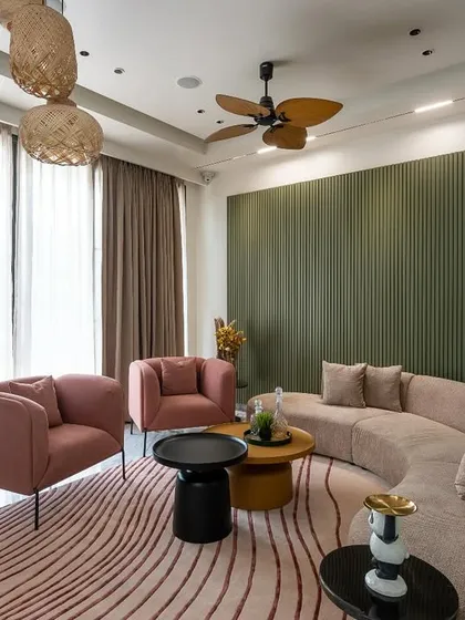 A cozy living space where a curved beige sofa is set against an olive green fluted wall. The design combines soft, sculptural furniture with natural textures and earthy tones for a warm, minimalist aesthetic.