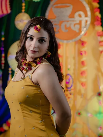 A lovely portrait of bride Nidhi at her Haldi ceremony. We captured her looking over her shoulder against the colourful backdrop of her Haldi decor.