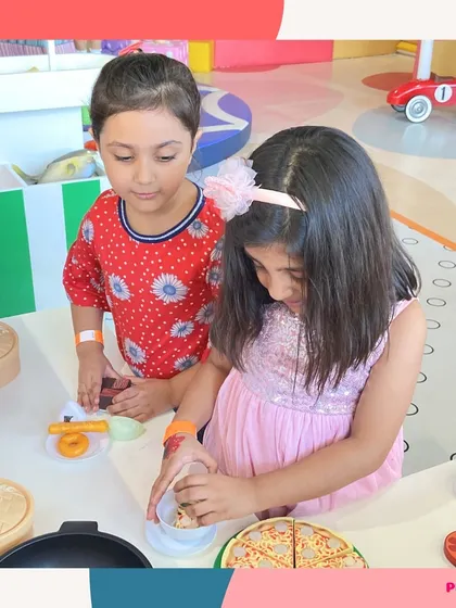 Playing is more fun with friends. Two girls work together to prepare a meal at our pretend food station.