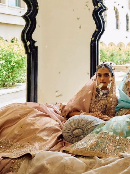 An editorial shot from a campaign, featuring a model with a traditional and clean bridal hairstyle that complements the royal setting and designer lehenga.