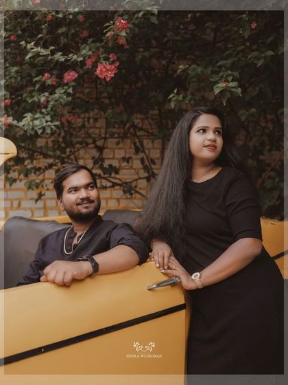 A framed portrait of a couple by a vintage yellow car, capturing a moment of relaxed intimacy.
