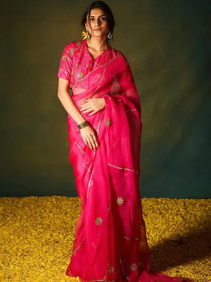 A vibrant pink organza saree with subtle gold motifs, creating a look that is both modern and elegant.