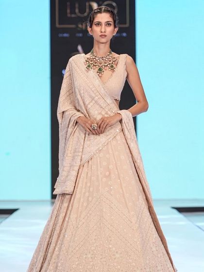 A regal and elegant look for a chikankari lehenga. The makeup is understated and sophisticated, with a sleek updo to draw attention to the stunning emerald necklace.