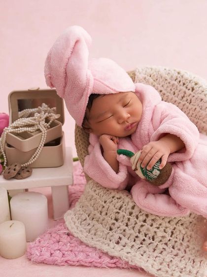 A close-up of our spa baby, showing the adorable details of the tiny pink robe, towel, and miniature coffee cup prop.