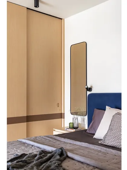 Another view of the bedroom, showing the minimalist bedside table and the sleek, modern mirror. The space is uncluttered and calming.
