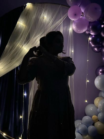 A guest making a heart shape with her hands, silhouetted against the beautiful lights and decorations.