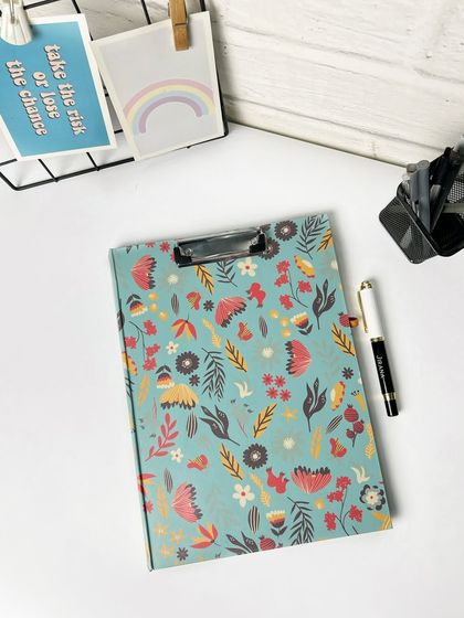 Another angle of the floral clipboard, showing more of the desk setup. The clean, white aesthetic is very popular for stationery brands.