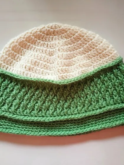 The two-tone green and cream Sheldon beanie laid flat. This view clearly shows the textured panel that makes this design unique.