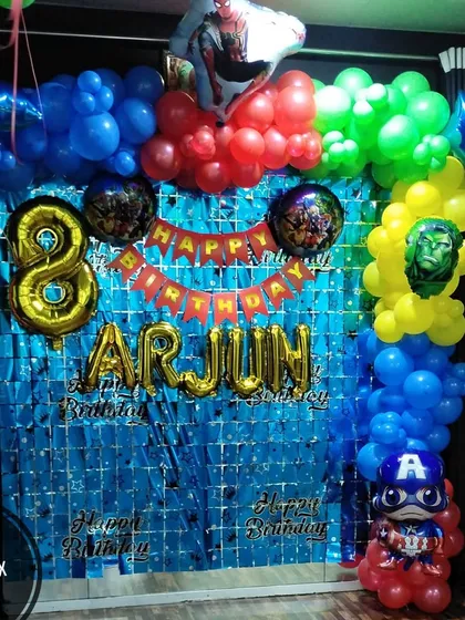 An Avengers-themed birthday party at home for Arjun's 8th birthday. This compact setup includes a blue fringe backdrop and a balloon arch with superhero accents.