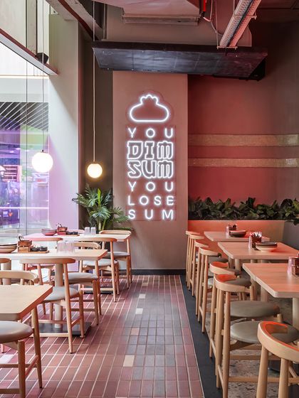 The playful "You Dim Sum You Lose Sum" neon sign is a central branding element. Its bright glow and witty phrase make it a memorable feature that perfectly captures the restaurant's fun-loving spirit.