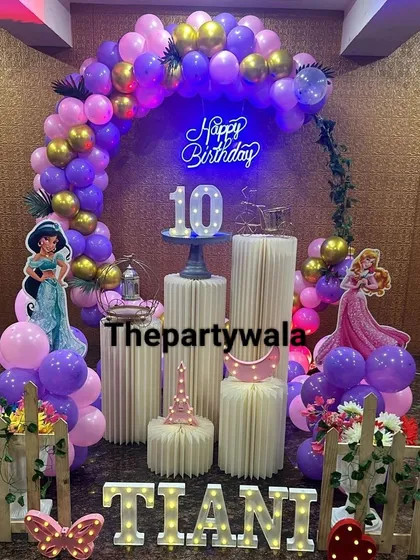 A grand princess theme for a 10th birthday, featuring a large balloon arch and a light-up number. The purple and gold colors give it a very royal and celebratory feel.