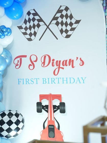 A close-up of the custom-designed backdrop for our car-themed birthday party, featuring checkered flags and a classic race car graphic for an authentic look.