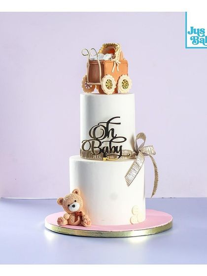 Welcoming a new baby is a joyous occasion. This two-tier baby shower cake has a clean, minimalist design, topped with an adorable edible baby carriage and a sweet teddy bear.